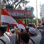Massa aksi 212 yang berdatangan ke Monas membawa bendera hingga spanduk. Satu di antaranya bertuliskan Ayo Tumbangkan Rezim Korup.